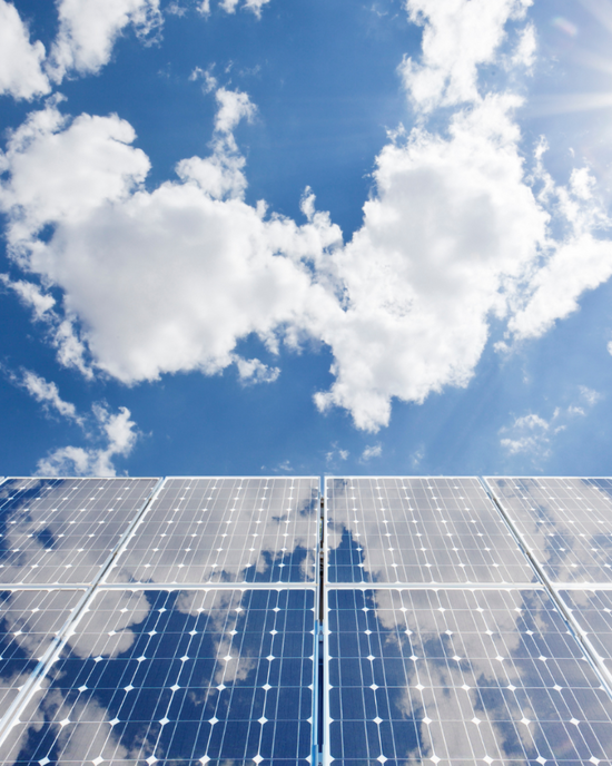Blue sky with fluffy white clouds about solar panels tilted up